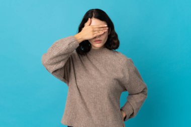 Genç Ukraynalı bir kız mavi arka planda, gözleri elleriyle kapatıyor. Bir şey görmek istemiyorum.