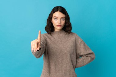 Genç Ukraynalı kız mavi arka planda izole edilmiş, ciddi ifadeli birini sayıyor.