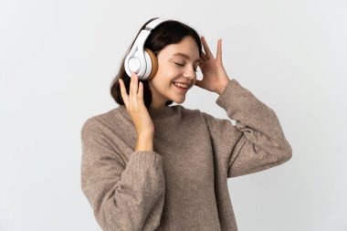 Genç Ukraynalı kız beyaz arka planda izole edilmiş müzik dinliyor ve şarkı söylüyor.