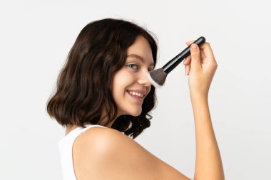 Genç Ukraynalı kız beyaz arka planda izole edilmiş elinde makyaj fırçası ve mutlu bir ifade var.