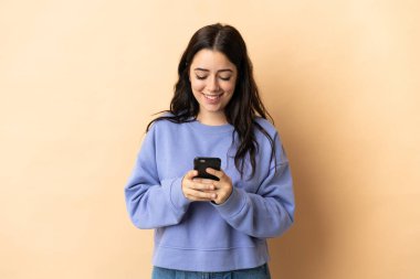 İzole edilmiş geçmişi olan beyaz bir kadın cep telefonuyla mesaj gönderiyor.