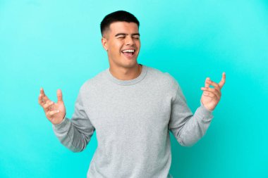 Soyutlanmış mavi arka planda genç yakışıklı adam çok gülümsüyor.