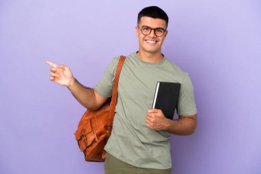 Tecrit edilmiş arka planda yakışıklı bir öğrenci parmak işareti yapıyor.