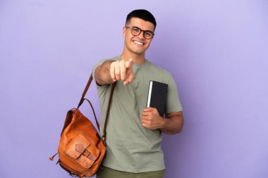 Soyutlanmış arka planda yakışıklı bir öğrenci, mutlu bir ifadeyle öne bakıyor.