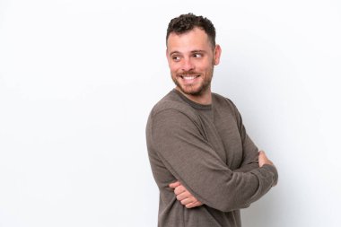 Genç Brezilyalı bir adam beyaz arka planda izole edilmiş, yana bakıyor ve gülümsüyor.