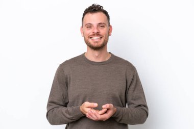 Genç Brezilyalı adam beyaz arka planda izole edilmiş gülüyor.