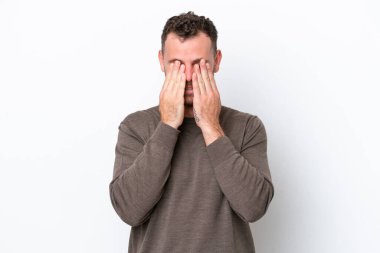 Genç Brezilyalı bir adam beyaz arka planda izole edilmiş, gözleri elle kapatılmış.