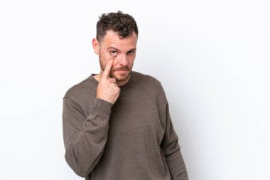 Beyaz arka planda izole edilmiş genç Brezilyalı bir adam bir şey gösteriyor