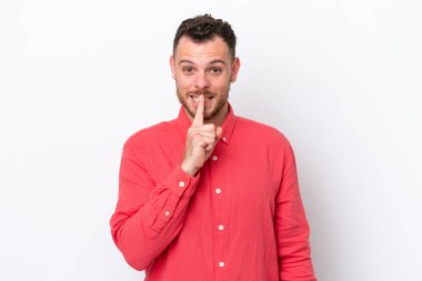 Beyaz arka planda izole edilmiş genç Brezilyalı bir adam sessizlik işareti gösteriyor. Parmağını ağzına sokuyor.