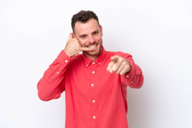 Beyaz arka planda izole edilmiş genç Brezilyalı bir adam telefon hareketi yapıyor ve ön tarafı işaret ediyor.