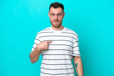 Mavi arka planda izole edilmiş genç Brezilyalı adam kendini işaret ediyor.