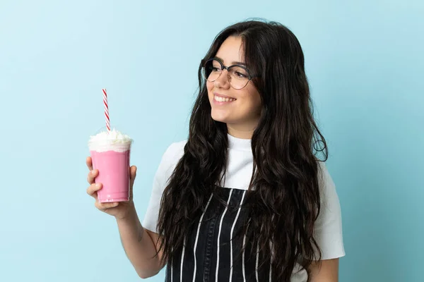 Ung Kvinna Med Jordgubbsmjölkshake Isolerad Blå Bakgrund Tittar Sidan Och — Stockfoto