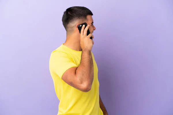 Молодой Красивый Мужчина Помощью Мобильного Телефона Изолированном Фиолетовом Фоне Смеется — стоковое фото