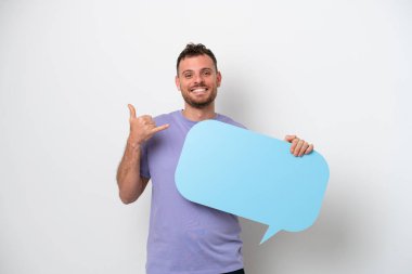 Beyaz arka planda izole edilmiş genç Brezilyalı bir adam boş bir konuşma balonu tutuyor ve telefon jesti yapıyor.