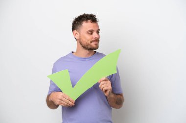 Beyaz arka planda izole edilmiş genç Brezilyalı bir adam elinde bir çek simgesi ve bir kenarı tutuyor.