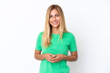 Sarışın Uruguaylı kız beyaz arka planda yalnız gülüyor.