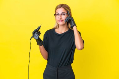 Dövme sanatçısı Uruguaylı kadın sarı arka planda bir fikir düşünüyor.