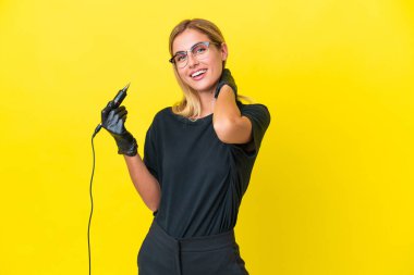 Dövme sanatçısı Uruguaylı kadın sarı arka planda izole bir şekilde gülüyor