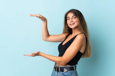 Mavi arka planda izole edilmiş beyaz bir kadın ilan vermek için kopyalama alanı tutuyor.