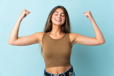 Mavi arka planda izole edilmiş beyaz bir kadın güçlü bir jest yapıyor.