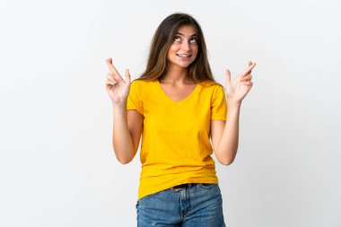 Beyaz arka planda izole edilmiş beyaz tenli genç bir kadın parmaklarını çapraz yapıp en iyisini diliyor.