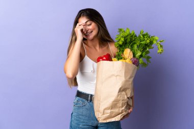 Alışveriş torbası tutan genç bir kadın gülüyor.