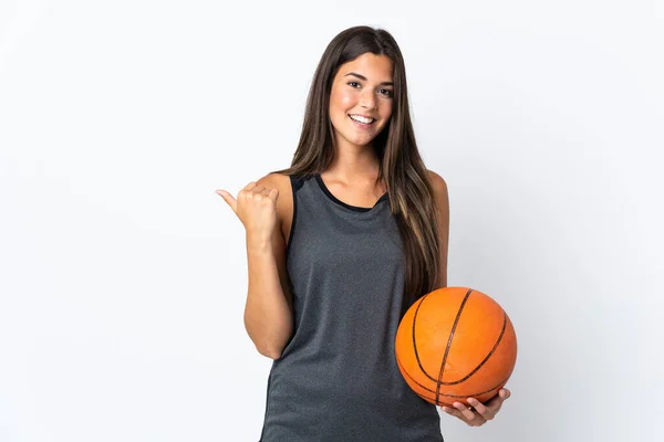 プロダクトを提示するために側面を指す白い背景に隔離されたバスケットボールをしている若いブラジル人女性 — ストック写真