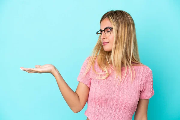 Loira Uruguaia Menina Isolada Fundo Azul Segurando Copyspace Com Dúvidas — Fotografia de Stock