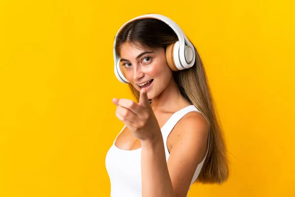 Νεαρή Καυκάσια Γυναίκα Απομονωμένη Κίτρινο Φόντο Ακούγοντας Μουσική Και Δείχνοντας — Φωτογραφία Αρχείου