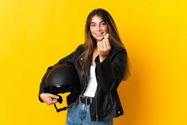 女性保持Aオートバイヘルメット隔離上の黄色の背景作るお金ジェスチャー — ストック写真