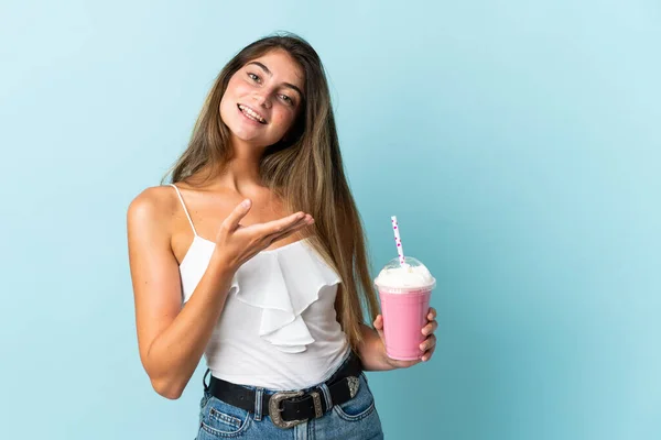 Ung Kvinna Med Jordgubbsmjölkshake Isolerad Blå Bakgrund Sträcker Händerna Sidan — Stockfoto