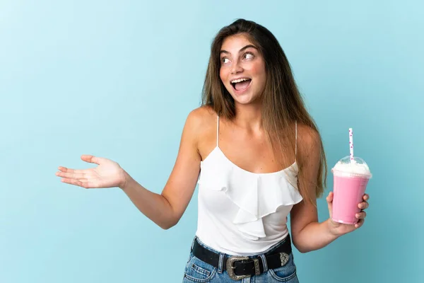 Ung Kvinna Med Jordgubbsmjölkshake Isolerad Blå Bakgrund Med Chockad Ansiktsuttryck — Stockfoto