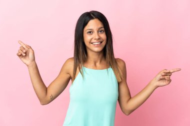 Pembe arka planda izole edilmiş beyaz kız parmak uçlarını işaret ediyor ve mutlu.