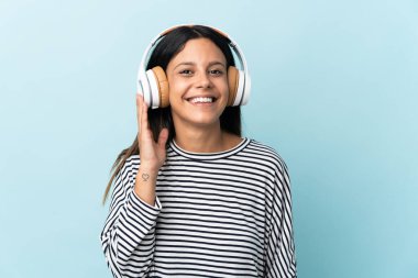 Beyaz kız mavi arka planda izole edilmiş müzik dinliyor.