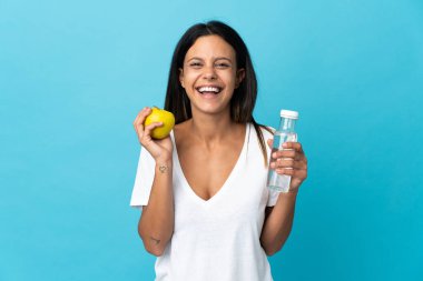 Beyaz kız mavi arka planda bir elma ve bir şişe suyla izole edilmiş.
