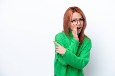 Beyaz arka planda izole edilmiş genç bir Rus kız bir ürün sunmak ve bir şeyler fısıldamak için kenarı işaret ediyor.