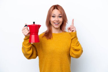 Beyaz arka planda kahve demliği tutan genç Rus kız harika bir fikre işaret ediyor.