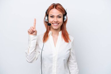 Beyaz arka planda izole edilmiş bir kulaklıkla çalışan pazarlamacı Rus kız en iyinin işaretini gösteriyor ve parmağını kaldırıyor.