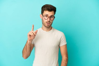 Genç, beyaz, yakışıklı bir adam mavi arka planda izole edilmiş.