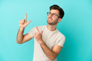 Mavi arka planda izole edilmiş genç beyaz adam işaret parmağıyla işaret etmek harika bir fikir.