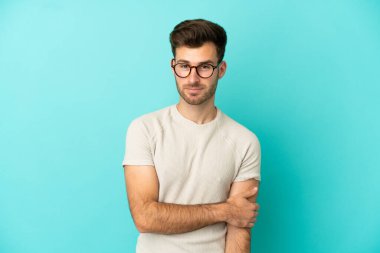 Genç beyaz yakışıklı adam mavi arka planda izole edilmiş gülüyor.