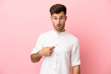 Pembe arka planda izole edilmiş beyaz tenli yakışıklı bir adam kendini işaret ediyor.