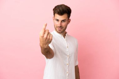 Pembe arka planda izole edilmiş beyaz, yakışıklı genç bir adam geliyor.