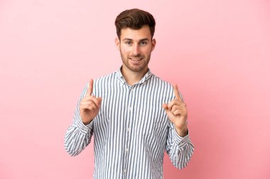 Pembe arka planda izole edilmiş beyaz, yakışıklı genç adam harika bir fikre işaret ediyor.