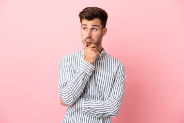 Pembe arka planda soyutlanmış beyaz, yakışıklı genç bir adam. Şüpheleri ve düşünceleri var.