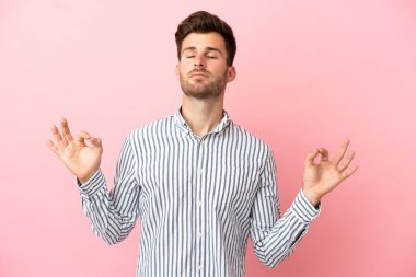 Zen pozisyonunda pembe arka planda izole edilmiş beyaz yakışıklı bir adam.