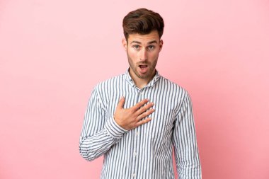 Pembe arka planda izole edilmiş beyaz, yakışıklı genç adam sağa bakarken şaşırmış ve şok olmuştu.