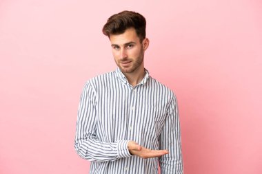 Pembe arka planda soyutlanmış beyaz, yakışıklı genç bir adam gülümserken bir fikir sunuyor.
