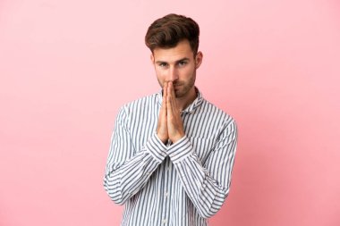 Pembe arka planda izole edilmiş beyaz tenli yakışıklı adam avuç içlerini bir arada tutuyor. İnsan bir şey ister.