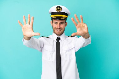 Kafkasyalı uçak pilotu mavi arka planda izole edildi. Parmakları olan dokuz kişi saydım.